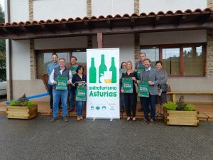 Foto socios y miembros Club de Producto Sidraturismo Asturias con el cartel, exterior del Llagar de Sidra Cortina