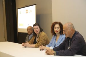Cuatro personas sentadas tras una mesa, realizando la presentación de un proyecto